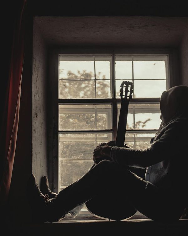 Person sitting peacefully by a window at dusk.